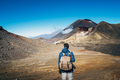 Rear view of man standing on mountain against sky