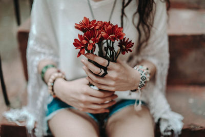 Female hands holding a bouquet of fresh red flowers. hippie summer concept