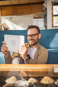 Young man using mobile phone while sitting on table