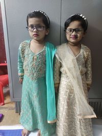 Portrait of girls standing against closet