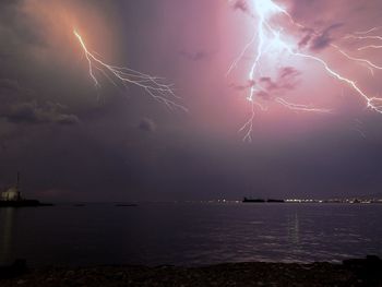 Firework display over sea against sky at night