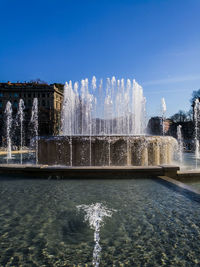 Fountain in front of built structure against sky