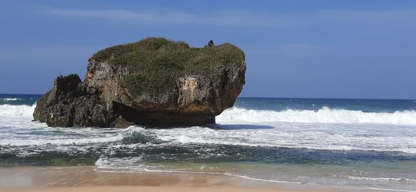 Rock formation on beach against sky