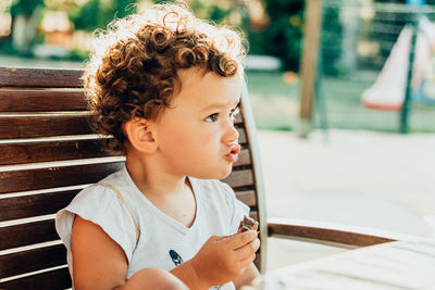 Cute girl eating chocolate looking away while sitting at restaurant