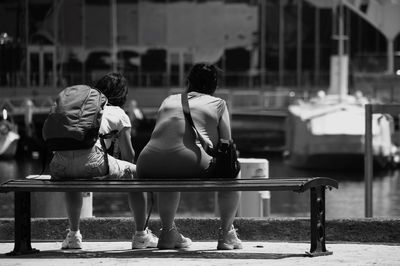 Rear view of people sitting on bench in city