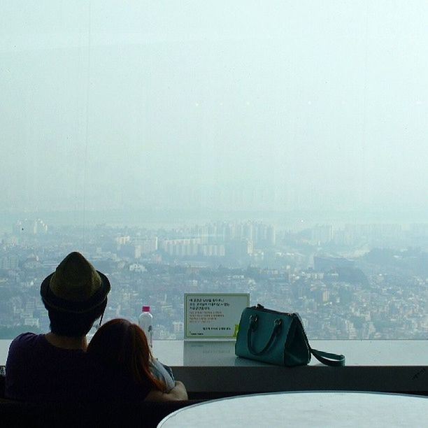 sitting, rear view, lifestyles, men, copy space, city, built structure, architecture, leisure activity, winter, fog, cityscape, waist up, weather, looking at view, relaxation, building exterior