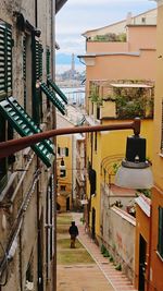 Rear view of woman walking on street amidst buildings in city