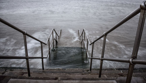 High angle view of metal railing by sea