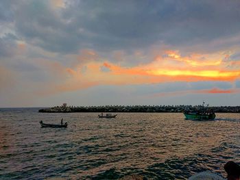 Boats sailing in sea against sky during sunset