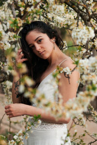 Portrait of young woman standing against plants