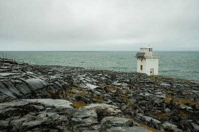 Lighthouse by sea against sky