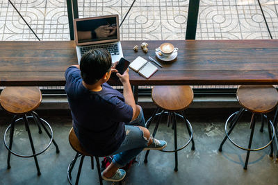 Rear view of man sitting on table