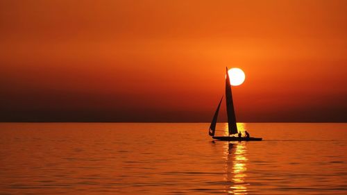 Boat sailing in sea at sunset