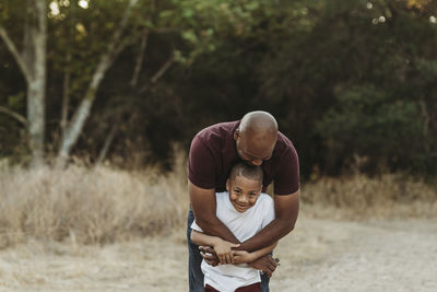 Close up of happy father and son hugging in backlit field