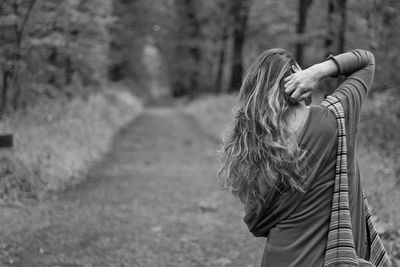 Rear view of woman with long hair standing on footpath