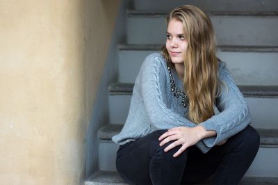 Young woman looking away while sitting on steps