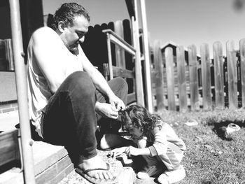 Full length of father with daughter sitting outdoors