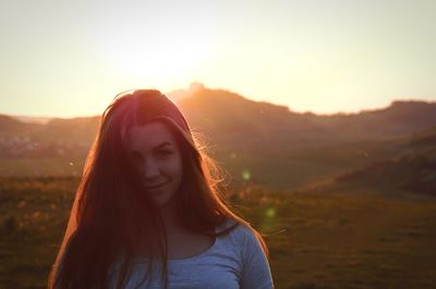 Portrait of young woman standing against sky during sunset