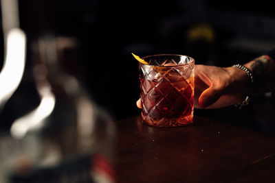 Close-up of hand holding drink on table