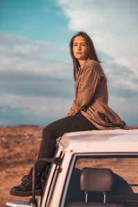 Portrait of woman sitting on land against sky