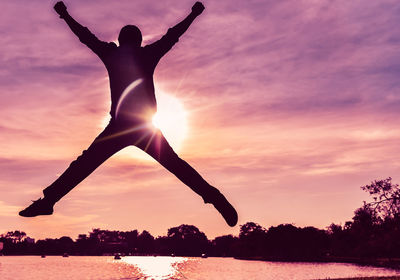 Silhouette man jumping against sky during sunset