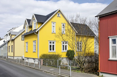 Street in the old town with a traditional house with a bright yellow corrugated metal facade