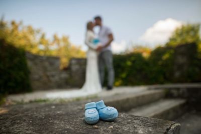 Close-up of baby booties on rock against couple