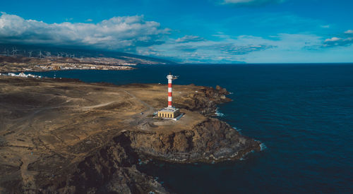 Lighthouse by sea against sky