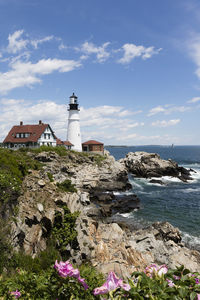 Lighthouse by sea against sky