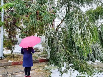 Rear view of woman standing on snow covered landscape during rainy season