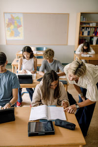 Female professor helping girl in high school classroom