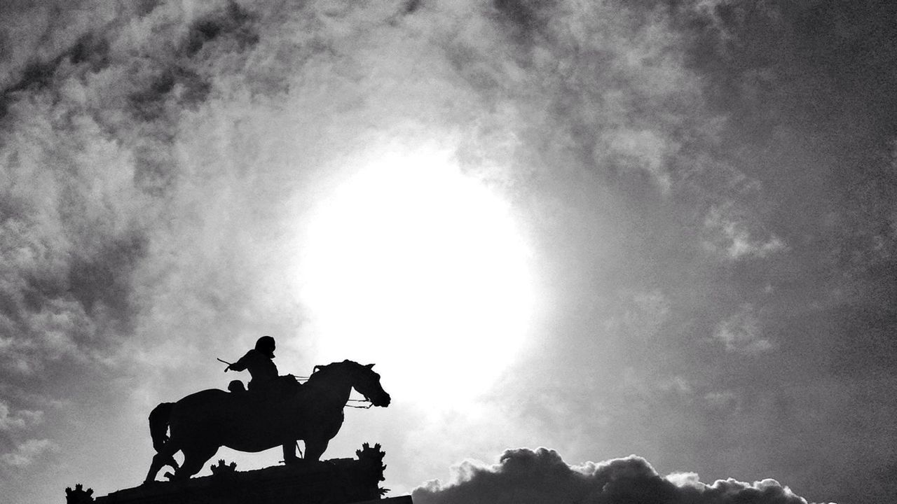 low angle view, sky, silhouette, statue, cloud - sky, sculpture, human representation, animal themes, cloudy, art and craft, art, animal representation, horse, cloud, creativity, outdoors, nature, day, no people