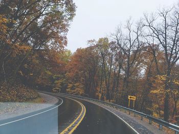 Road amidst trees against sky during autumn