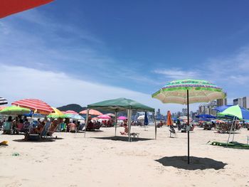 People at beach umbrellas against blue sky