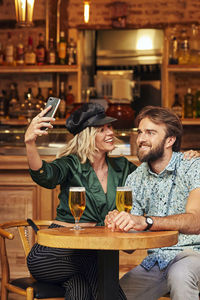 Man and woman using phone while sitting in restaurant