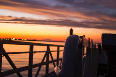 Close-up of railing against sea during sunset