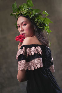 Young woman looking away while standing against plants