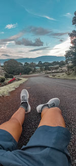 Low section of man on road against sky