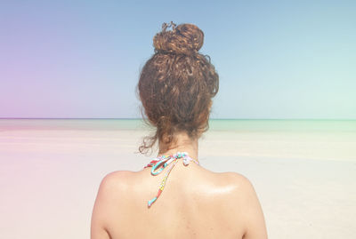 Rear view of woman standing at beach against sky