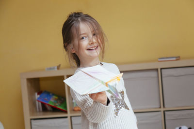 Portrait of smiling girl playing with paper airplane