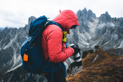 Side view of man holding camera against mountain range