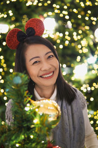 Portrait of young woman holding christmas tree