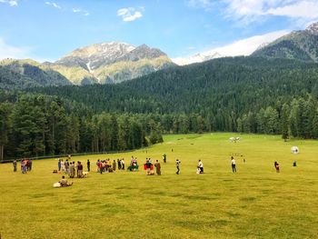 Group of people on field against mountains