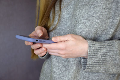 Young woman holds smartphone in her hands. she browses website information on mobile phone screen.