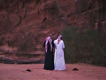 Rear view of men wearing traditional clothing while standing in desert