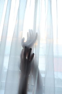 Close-up of human hand against curtain