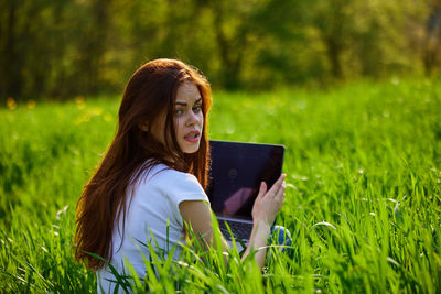 Portrait of young woman sitting on field