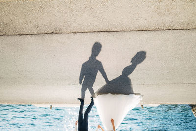 Shadow of man and woman standing by sea