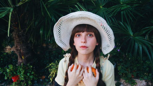 Close-up portrait of young woman wearing hat against plants