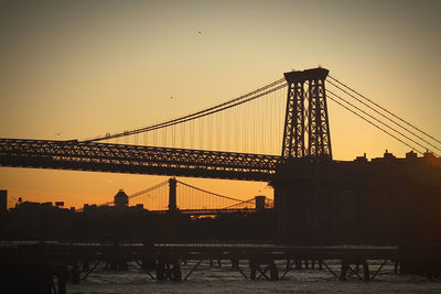 Silhouette of suspension bridge against sky during sunset